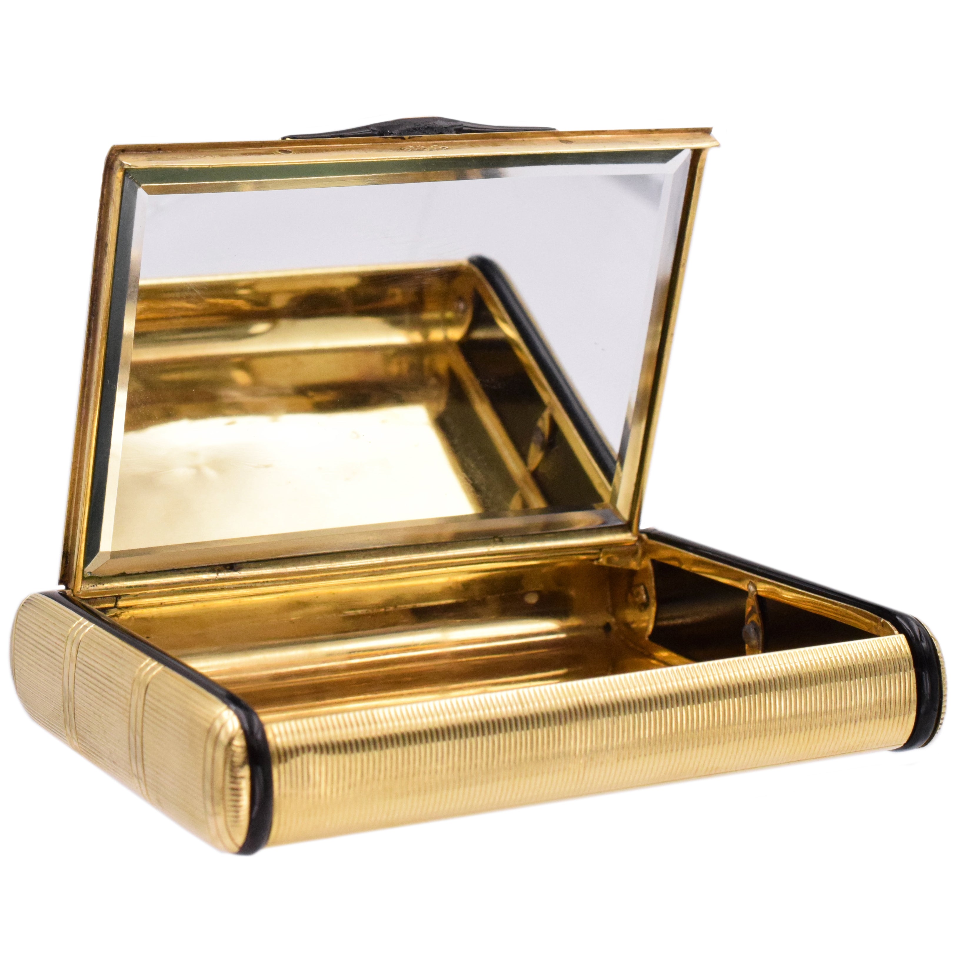 Compact mirror box by Cartier, crafted in 18k yellow gold, beautifully engraved with decorative vertical and horizontal lines throughout the box. Sides of the compact are accented with black onyx shaped into elongated discs with rounded corners, and black enamel on the snap closure lock. Inside equipped with a crystal beveled edge mirror. Measurements 3.5" by 2.6" x 0.6" (89mm x 66mm x 16mm) Signed Cartier and serial number. Stamped 750 for 18k gold. Weight 147.6g. Ref# 950-000-168